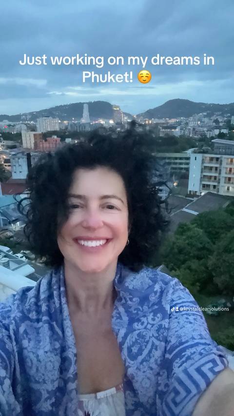       Person smiling with a blurry cityscape in the background.
  