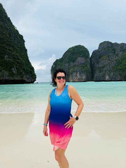       Person standing on a beach with dramatic cliffs.
  