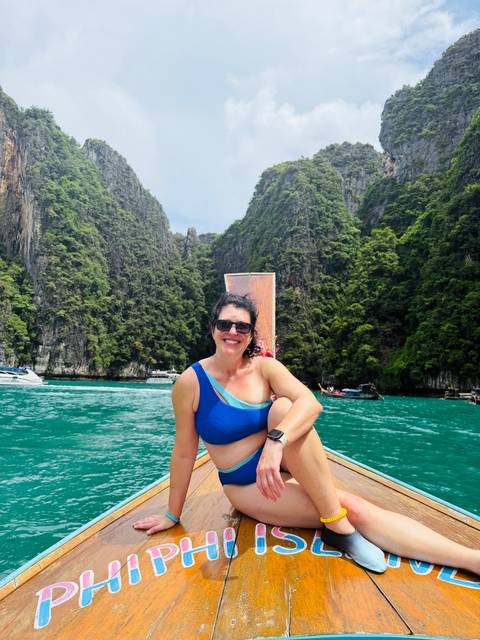 Person on a boat enjoying a scenic view of limestone cliffs.