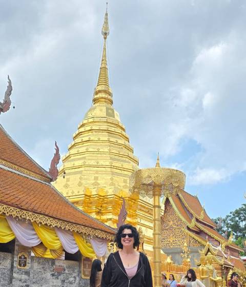 A golden temple with intricate architecture against the blue sky.