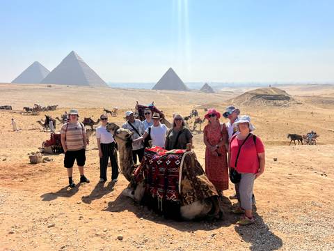 A large group of tourists with pyramids in the background.