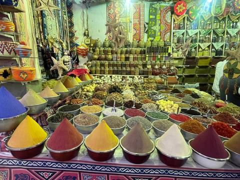Variety of colorful spices displayed in bowls at a market.