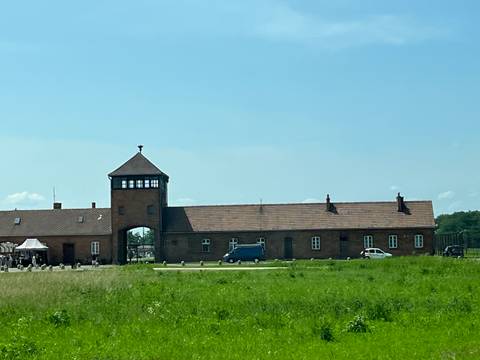       A brick entrance to a historical site with a tower.
  