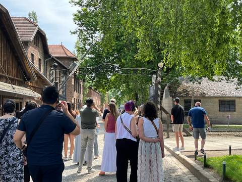       Tourists visiting an outdoor historical site with a gate entrance.
  
