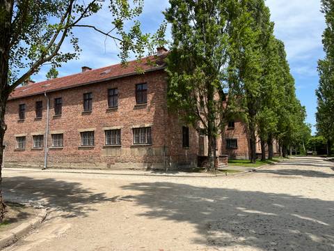       A red brick building surrounded by trees under a bright sky.
  