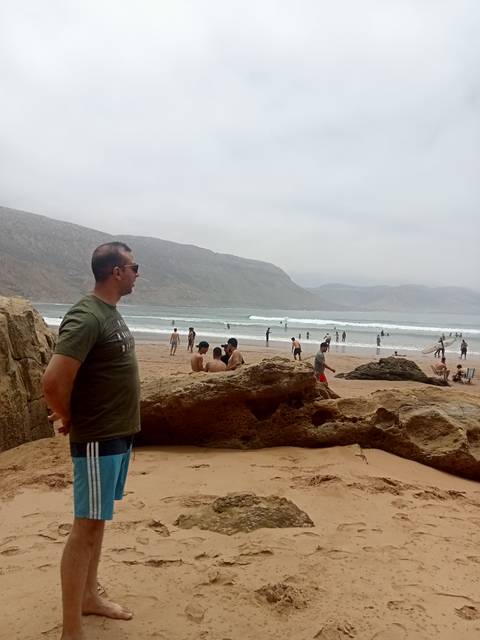       A beach scene with people and waves in Morocco.
  