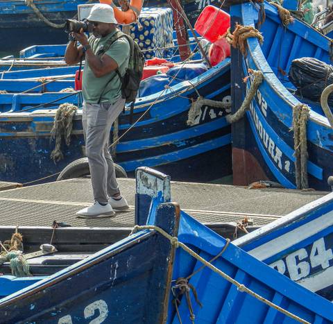 Close-up of blue fishing boats with a person walking.