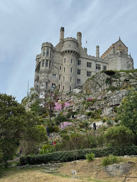 A magnificent castle built on a rocky hill with gardens below.