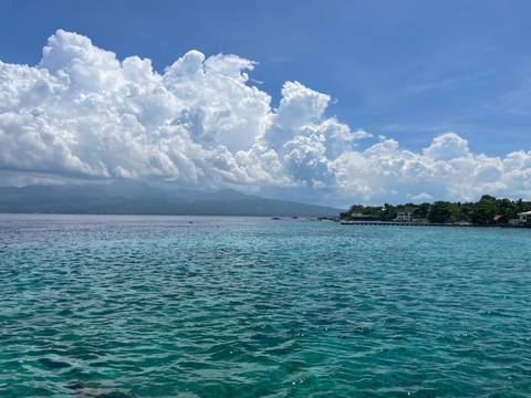 A clear coastal view with turquoise water and distant mountains.