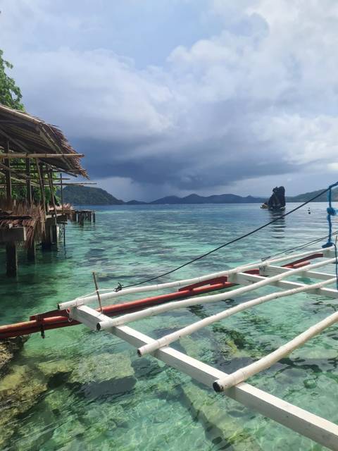 A tropical view from a hut over clear blue water and distant islands.