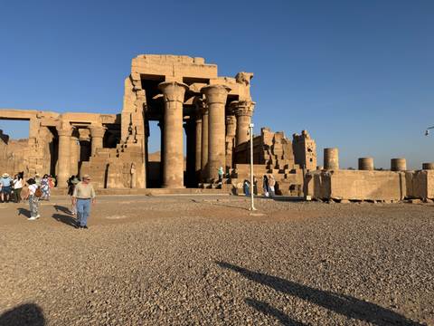       Kom Ombo Temple with stone columns and tourists.
  