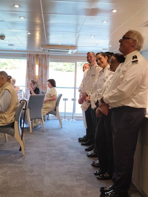 Restaurant setting on a cruise with staff standing.