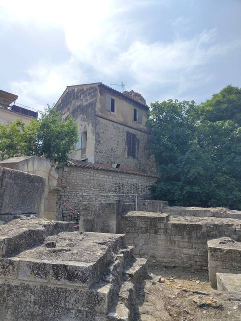 Old building with a stone facade surrounded by trees.