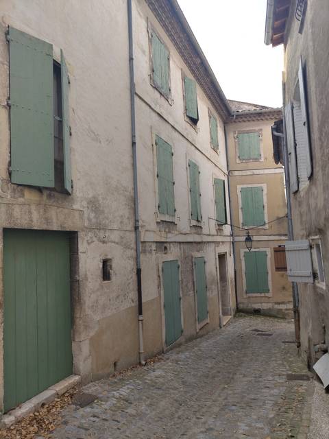 Narrow alley with shuttered windows and aged walls.