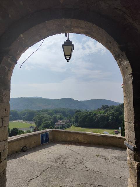       View through an archway to rolling hills and forest.
  