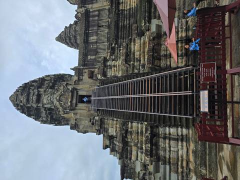       A stone temple with tall steps leading to the entrance, with a person standing at the top.
  