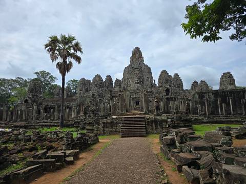       Angkor Thom ruins with towering structures surrounded by greenery.
  