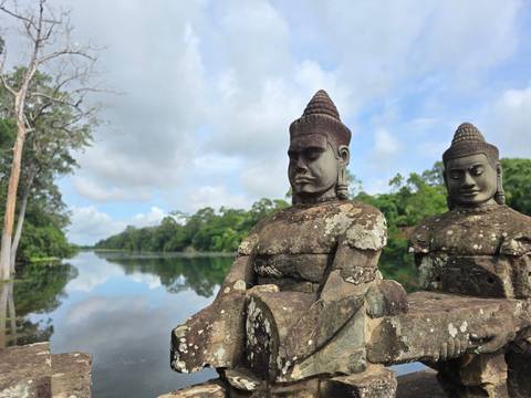 Statues of deities by a serene lake.