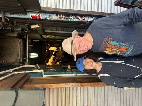       Two people smiling outside a restaurant alleyway.
  