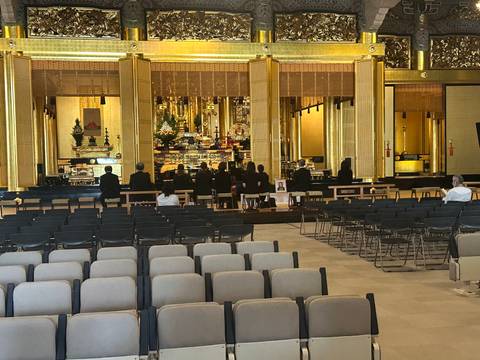 Interior of a Buddhist temple with people sitting in rows.