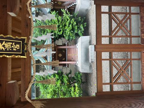       Shinto shrine at the end of a pathway, surrounded by greenery.
  