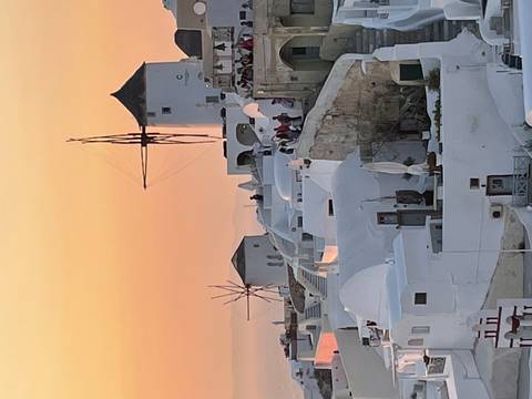 Sunset view of white buildings and windmills in Santorini.