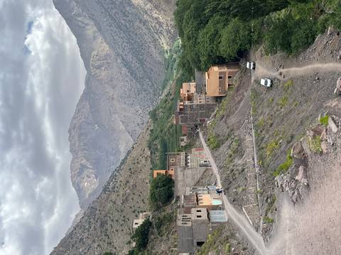 Mountainous village scene with cars and traditional buildings.