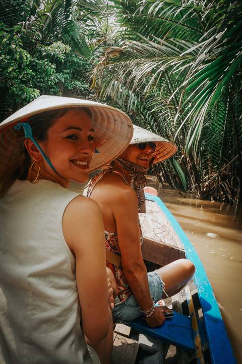       Two people enjoying a boat ride through a tropical river.
  