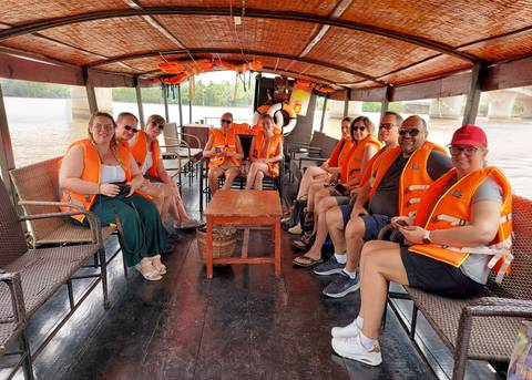       Group of people wearing life vests enjoying a boat ride.
  