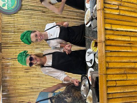       Two people in aprons enjoying a cooking class, smiling.
  