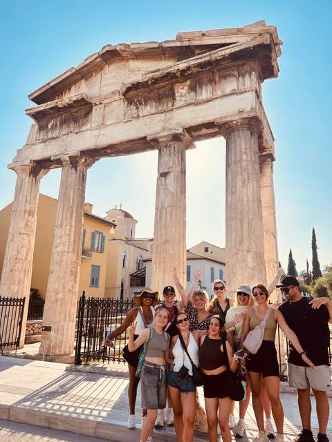Group of people posing in front of an ancient structure in Greece.