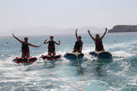 Four people on inflatable tubes being towed in the sea.