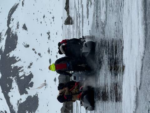       Small boat with people navigating icy waters.
  