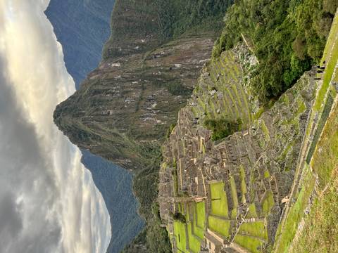 View of Machu Picchu with terraces and high peak.