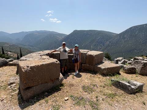       Couple posing at ancient ruins with mountains in the background.
  