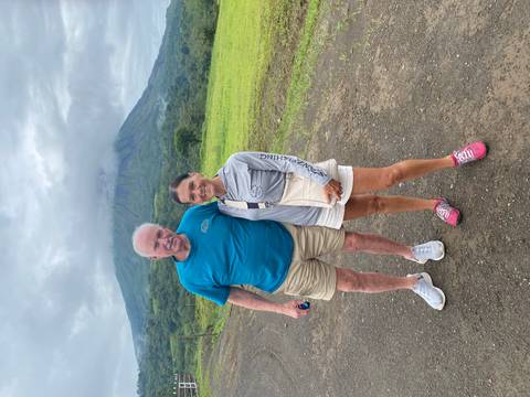 A couple posing in front of a prominent volcano.