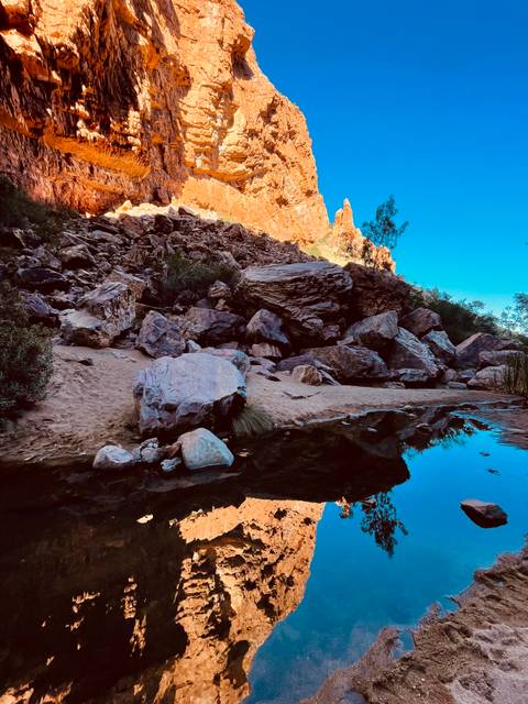       Landscape with rocks, sand, and a reflecting pool of water.
  