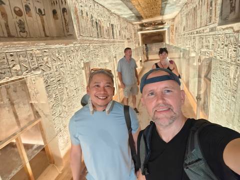 Tourists exploring an ancient corridor decorated with hieroglyphs.