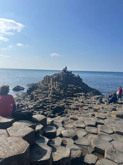       Tourists atop Giant's Causeway looking at the ocean.
  