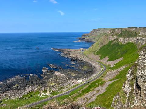 Scenic coastal view with lush cliffs and a winding road.