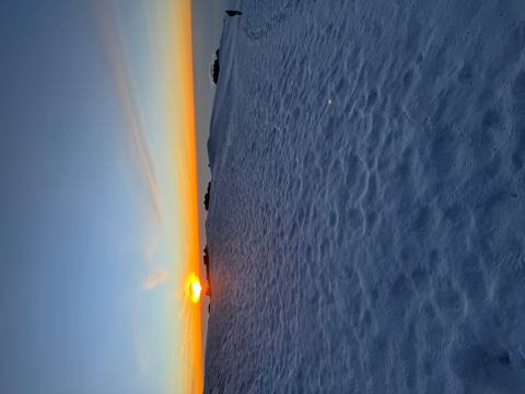 Snow-covered landscape during sunrise with a clear sky.