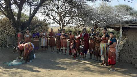       Group of people in traditional attire in a rural setting.
  
