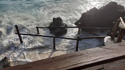       Wooden staircase leading to a crashing wave.
  