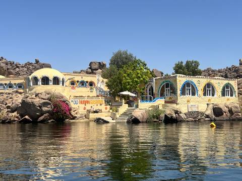 Colorful, decorated houses by a river with rocky formations.