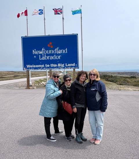 Four women posing in front of a Newfoundland and Labrador welcome sign.