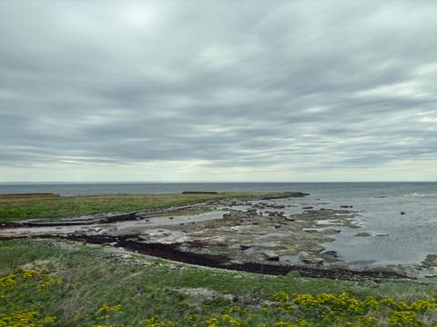Cloudy sky over a rocky shoreline with shallow water.