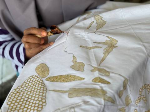       Person working meticulously on a handmade fabric design.
  