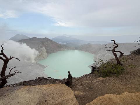       Crater lake with cloudy skies and distant mountains.
  