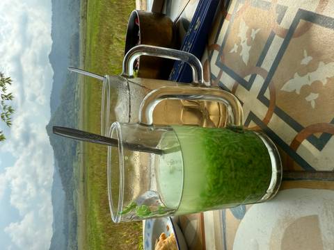       Two glasses with drinks on a table overlooking lush green scenery.
  
