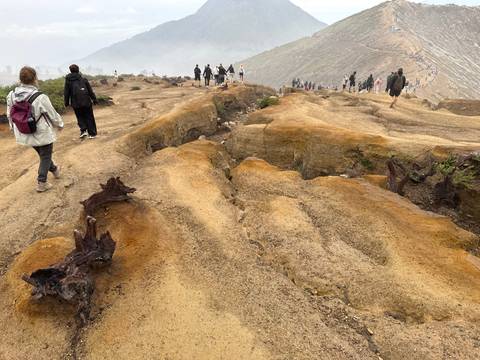       Group of people walking on a rocky path in an open landscape.
  
